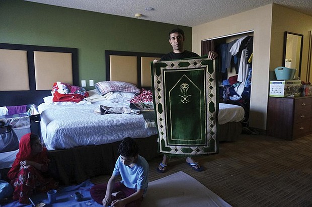 Khial Mohammad Sultani holds the prayer rug that is among his family’s most treasured possessions in the motel room in El Paso, Texas, where they now live. His father brought the rug from Mecca after another son was killed by the Taliban, Mr. Sultani said, and now he brought it to his new life in the United States.