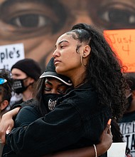 Two women embrace in front of a mural of George Floyd following the guilty verdict the trial of Derek Chauvin on April 20, 2021, in Atlanta, Georgia./Getty Images