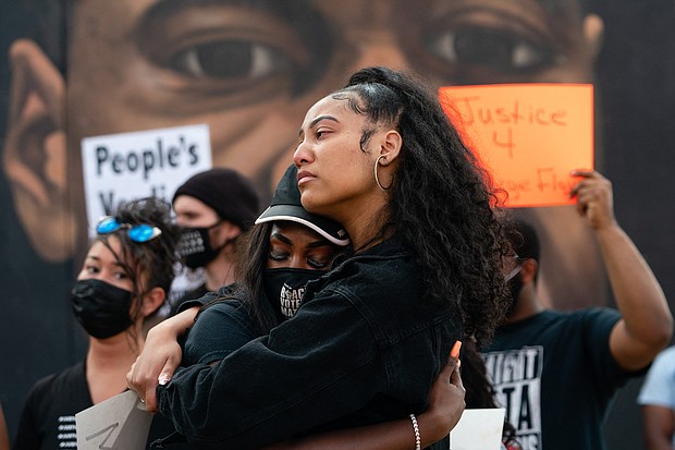 Two women embrace in front of a mural of George Floyd following the guilty verdict the trial of Derek Chauvin on April 20, 2021, in Atlanta, Georgia./Getty Images