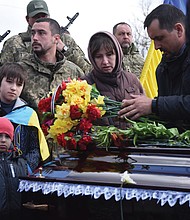 Relatives and friends stand by the coffins of Ukrainian servicemen Yuri Filyuk, 49, and Oleksander Tkachenko, 33, during a funeral ceremony Tuesday in a village of Oleksandrivka, Odesa region, Ukraine. According to Ukrainian servicemen, these two were killed when a Russian missile hit their military base in Krasnoselka, Odesa region, on April 7.