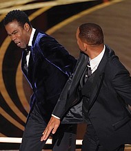 Will Smith, right, hits presenter Chris Rock on stage while presenting the award for best documentary feature at the Oscars on Sunday, March 27.