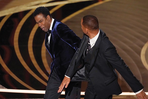 Will Smith, right, hits presenter Chris Rock on stage while presenting the award for best documentary feature at the Oscars on Sunday, March 27.