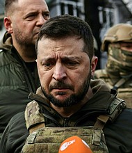 Ukainian President Volodymyr Zelensky, center, speaks to the press in the town of Bucha, northwest of the Ukrainian capital Kyiv, on Monday, April 4, 2022. (Ronaldo Schemidt/AFP/Getty Images/TNS)