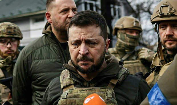 Ukainian President Volodymyr Zelensky, center, speaks to the press in the town of Bucha, northwest of the Ukrainian capital Kyiv, on Monday, April 4, 2022. (Ronaldo Schemidt/AFP/Getty Images/TNS)
