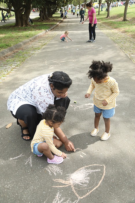 Courtney Johnson of Hopewell and her 2-year-old twins, Jayla and Leila, get creative with pastel sidewalk chalk on one of Maymont’s long walkways. They found a quiet space among the crowd to draw happy faces and other figures.