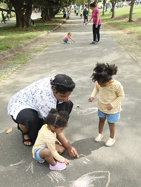 Courtney Johnson of Hopewell and her 2-year-old twins, Jayla and Leila, get creative with pastel sidewalk chalk on one of Maymont’s long walkways. They found a quiet space among the crowd to draw happy faces and other figures.
