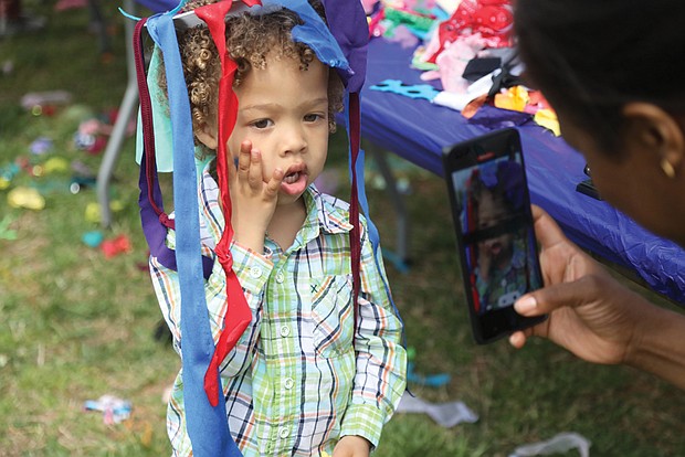 Esther Howard turns her son Levi’s moment into memories as she photographs the 3-year-old wearing the Easter creation he fashioned from streamers. The Howard family, including dad and 10-month-old sister Edin, drove down from Stafford to attend the event.