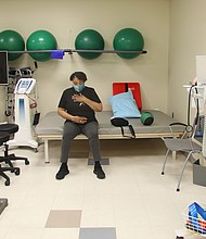 Natarsha Eppes-Kelly sits to catch her breath after completing physical therapy exercises with a weighted four-pound ball. Her therapist, Dr. Jason Seltzer, enters on his computer notes about her progress. Ms. Eppes-Kelly has been undergoing physical therapy at Sheltering Arms Physical Rehabilitation and Therapy Center in Bon Air.