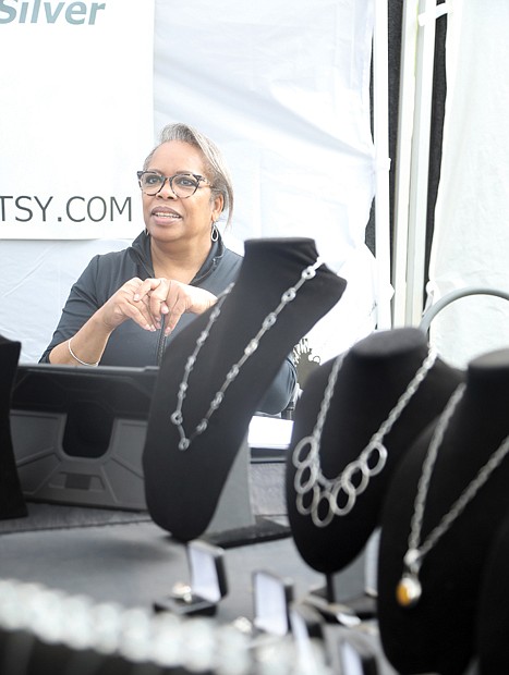 Surgical tech-turned-artist Melanie Taliaferro of Chesterfield County shows off her handmade necklaces, earrings and other jewelry as customers weave in and out of her tent. She said she hung up one set of tools 15 years ago and opted for those of a metalsmith and jewelrymaker.