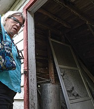 Kate Tweedy, an attorney and author, enters the cabin shrouded by trees and shrubs that still stands on the property once owned by her family.