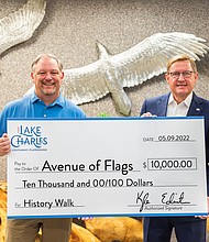 Kyle Edmiston, President/CEO of Visit Lake Charles, presents a $10,000 grant to Ted Harless, Jr., Director of the Avenue of Flags, to enhance the biannual event with the History Walk that will debut at the 2022 Avenue of Flags’ Memorial Day display.