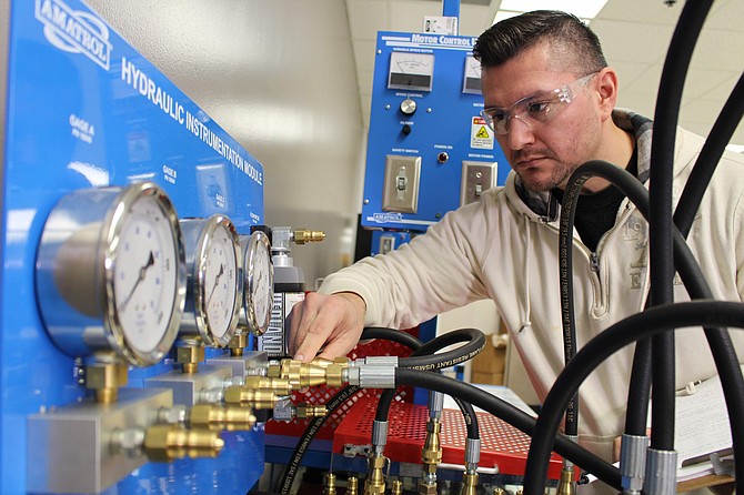 Former South Suburban College student adjusts a hydraulic instrumentation module.
