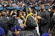 Zahria Brandon, center left, adjusts the academic hood of Taylor Robinson during Hampton University’s commencement last Sunday at the HU Convocation Center.