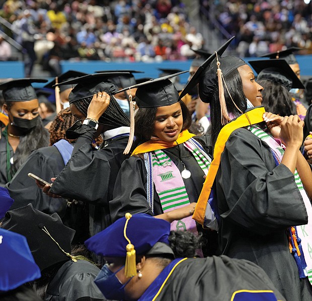 Zahria Brandon, center left, adjusts the academic hood of Taylor Robinson during Hampton University’s commencement last Sunday at the HU Convocation Center.