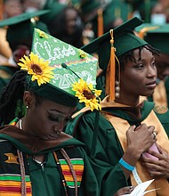 Makayla Taylor, left, and Searra Wiggins intently follow the commencement program.