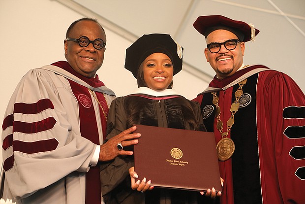 Social activist Tamika D. Mallory, who delivered the commencement address, smiles after receiving an honorary degree. She is flanked by Dr. W. Franklyn Richardson, left, chairman of the VUU Board of Trustees, and VUU President Hakim J. Lucas.