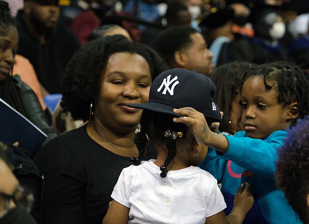 Malakai Sellers helps Melody Sellers try on his baseball cap during the 2022 Virginia State University Commencement ceremony last Saturday. The two were with family to see the graduation ceremony.
