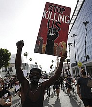 A protester carries a sign in the Hollywood area of Los Angeles on June 1, 2020, during demonstrations after the killing of George Floyd, which sparked calls for a racial reckoning to address structural racism that has created long-standing inequities impacting generations of Black Americans.