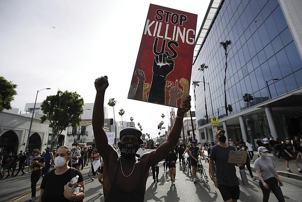 A protester carries a sign in the Hollywood area of Los Angeles on June 1, 2020, during demonstrations after the killing of George Floyd, which sparked calls for a racial reckoning to address structural racism that has created long-standing inequities impacting generations of Black Americans.