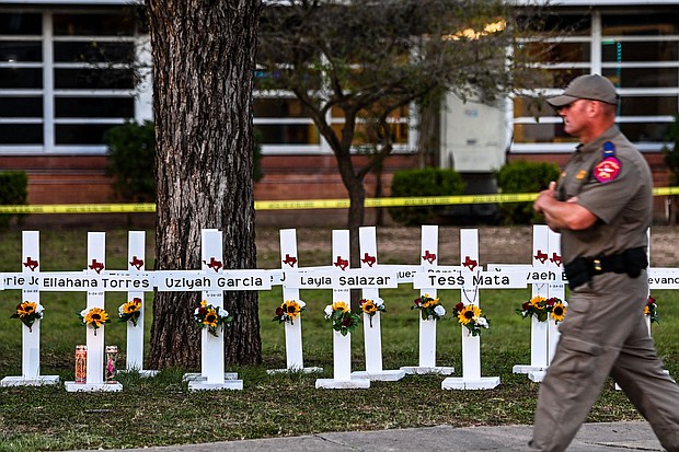 Police officers walk past a makeshift memorial for the shooting victims at Robb Elementary School in Uvalde, Texas, on Thursday.
Mandatory Credit:	Chandan Khanna/AFP/Getty Images