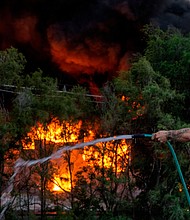 A fire that burned part of a chemical plant in Nebraska's most populous city led officials to urge some residents to evacuate the area, and pictured, a man sprays down the roof of a building that is near a chemical plant that was on fire on May 30 in Omaha, Nebraska.
Mandatory Credit:	Chris Machian/Omaha World-Herald/AP