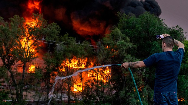 A fire that burned part of a chemical plant in Nebraska's most populous city led officials to urge some residents to evacuate the area, and pictured, a man sprays down the roof of a building that is near a chemical plant that was on fire on May 30 in Omaha, Nebraska.
Mandatory Credit:	Chris Machian/Omaha World-Herald/AP