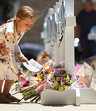 A young girl lays flowers on a make-shift monument
to the fallen children of Uvalde, Texas