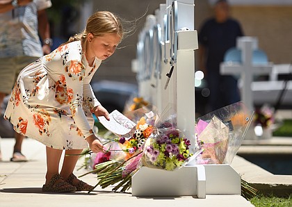 A young girl lays flowers on a make-shift monument
to the fallen children of Uvalde, Texas