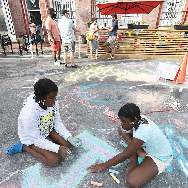 Ten-year-old twin sisters Alicia, left, and Alivia Odhimbo, focused on their creative chalk art skills during Art 180’s “The Big Show,” a block-style celebration hosted on June 3 at 114 W. Marshall St.