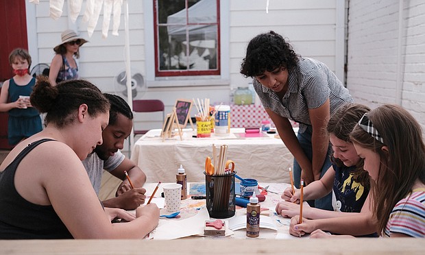 Celine Anderson of The Visual Arts Center bends to view artwork created by (from left) Raelyn Fines, Kerry Mason, Emily Barber and Caiden Storey during Oakwood Arts’ June 4 celebration of the renovated Oakwood Church in the city’s East End.