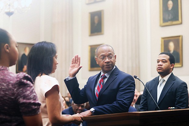 Chief Justice S. Bernard Goodwyn, center, holds his right hand up as his left hand is on the Bible held by his wife, Sharon S. Goodwyn, as his daughter Sarah E. Goodwyn, left, looks on along with his son Samuel J. Goodwyn during the administration of the oath Wednesday in the chambers of the Supreme Court of Virginia.
