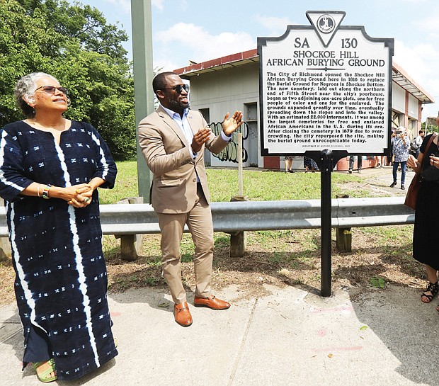 Mayor Levar M. Stoney takes part in unveiling new state history marker for the historic Shockoe Hill Burying Ground, the long forgotten public cemetery for 22,000 Black people at 1305 N. 5th St. at the entry to Highland Park. Joining the mayor at the ceremony Sunday afternoon are Ana F. Edwards of the Sacred Ground Historical Reclamation Project, left, and Lenora C. McQueen, a Texas resident who has led a four-year fight to preserve and protect the burial ground where relatives are buried and who has pushed for the cemetery’s recognition and designation as a national historic site.