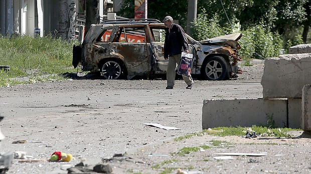 A man walks past the wreckage of a car in Lysychansk on June 21, as Ukraine says Russian shelling has caused "catastrophic destruction" in the eastern industrial city.
Mandatory Credit:	ANATOLII STEPANOV/AFP/AFP via Getty Images