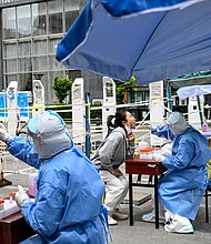 Health workers take swab samples to be tested for Covid-19 at a makeshift testing site along a street in Beijing on May 11.
Mandatory Credit:	Jade Gao/AFP/Getty Images