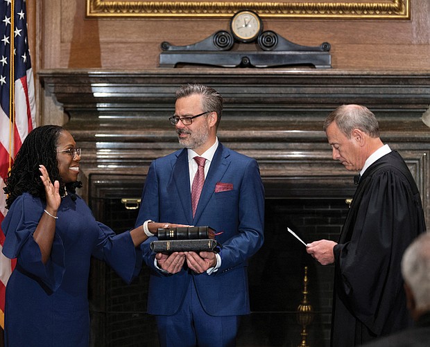 Judge Ketanji Brown Jackson takes her constitutional oath of office as an associate justice of the U.S. Supreme Court administered by Chief Justice John Roberts as Judge Jackson’s husband Patrick Jackson holds the Bible in a handout image provided by the U.S. Supreme Court from ceremonies held June 30 at the Supreme Court building in Washington.