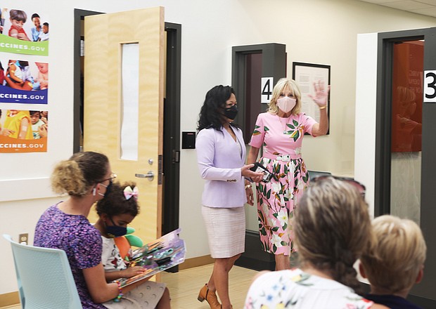 First Lady Jill Biden, right, waves to families waiting for their young children to be vaccinated at the Henrico County Health Department East Clinic on July 1. She is escorted by Dr. Melissa A. Viray, acting director of Richmond and Henrico health districts.