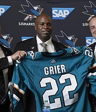 Mike Grier, middle, poses for photos Tuesday as he is introduced as the new general manager of the San Jose Sharks between assistant general manager Joe Will, left, and president Jonathan Becher at a news conference in San Jose, Calif.