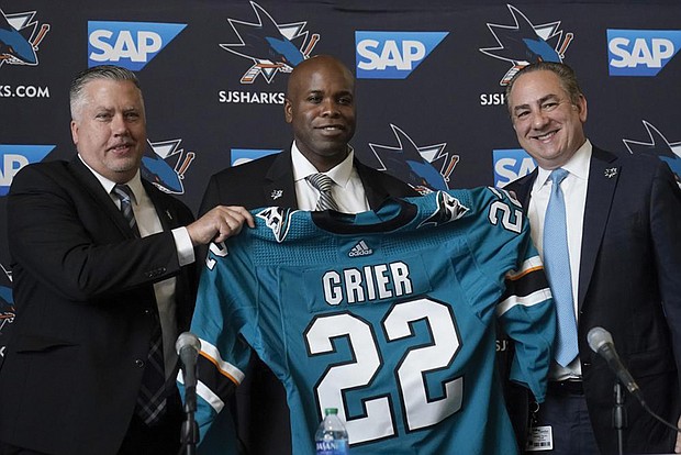Mike Grier, middle, poses for photos Tuesday as he is introduced as the new general manager of the San Jose Sharks between assistant general manager Joe Will, left, and president Jonathan Becher at a news conference in San Jose, Calif.