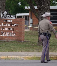 An officer walks outside of Robb Elementary School in Uvalde, Texas, on May 24.
Mandatory Credit:	Allison Dinner/AFP/Getty Images