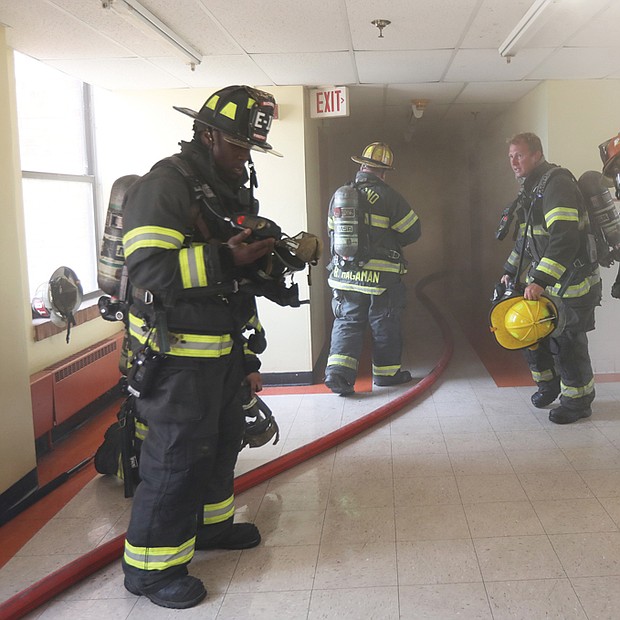 What may appear to be response to a fire is actually the Richmond Fire Department conducting high-rise fire training in the vacant, 11-story Frederic A. Fay Towers building in Gilpin Court. These firefighters just completed a fire simulation activity and are quickly removing their equipment to catch their breath and cool off.