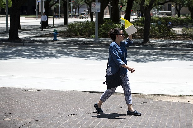 A pedestrian walks with a bag covering her face to block the sun during a heatwave in Houston, Texas.
Mandatory Credit:	Mark Felix/Bloomberg/Getty Images