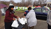 in this January 2020 photo, weeks before the COVID-19 pandemic struck, Ruvondai N. Brown, left, assists Rhonda L. Sneed in laying out supplies for residents of “Camp Cathy,” a homeless tent city on Oliver Hill Way. Richmond Mayor Levar M. Stoney had the camp torn down. Ms. Sneed, founder and executive director of Blessing Warriors, a nonprofit that provides food and clothing to the unsheltered, has been outspoken in her criticism of the city’s effort, saying that Richmond treats stray animals better than unsheltered humans. She believes that the best way to ensure sufficient shelter would be for the city to allow her to install a tent city akin to the Camp Cathy.