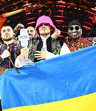 Members of the band Kalush Orchestra pose onstage with the winner's trophy and Ukraine's flags after winning on behalf of Ukraine the Eurovision Song Contest in May. The UK will host next year's Eurovision Song Contest on behalf of Ukraine.
Mandatory Credit:	Marco Bertorello/AFP/Getty Images