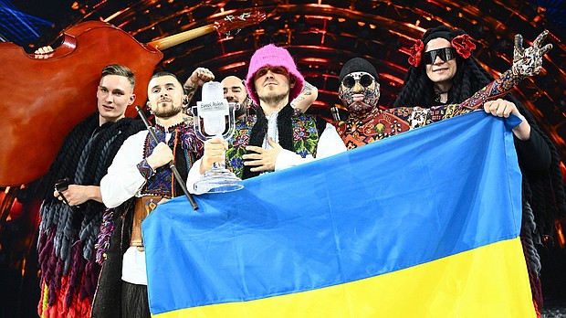 Members of the band Kalush Orchestra pose onstage with the winner's trophy and Ukraine's flags after winning on behalf of Ukraine the Eurovision Song Contest in May. The UK will host next year's Eurovision Song Contest on behalf of Ukraine.
Mandatory Credit:	Marco Bertorello/AFP/Getty Images