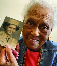 Romay Davis, 102, poses with a photo showing her during World War II, at her home in Montgomery, Ala. Mrs. Davis was honored on July 26 for her service with the all-female, all-Black 6888th Central Postal Directory Battalion, which got mail to U.S. troops in Europe during the war.