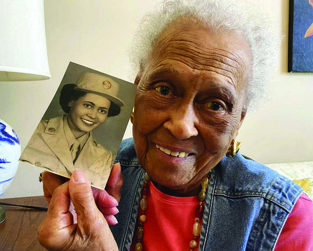 Romay Davis, 102, poses with a photo showing her during World War II, at her home in Montgomery, Ala. Mrs. Davis was honored on July 26 for her service with the all-female, all-Black 6888th Central Postal Directory Battalion, which got mail to U.S. troops in Europe during the war.