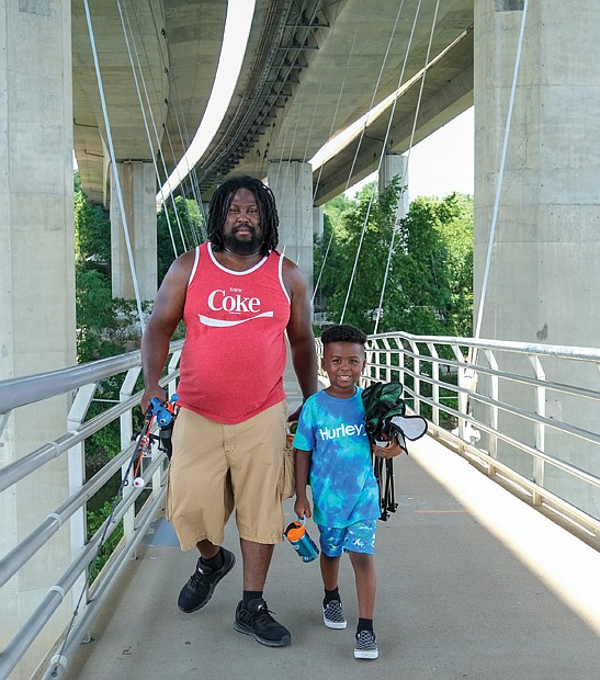 Father and son fishermen, Denzel Terrell and 6-year-old Deion Terrell, trek the pedestrian bridge from Brown’s Island to Belle Isle looking to land a big catch this summer.