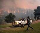 A man runs to a truck as a wildfire called the McKinney fire burns last week in Klamath National Forest, Calif.