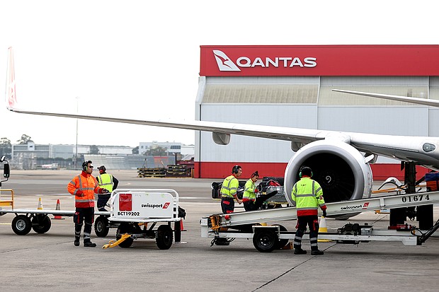 Members of the ground crew work next to an aircraft operated by Qantas Airways Ltd. at Sydney Airport in Sydney, Australia, on June 23, 2021.    Qantas has asked its senior executives to help out as airport baggage handlers as it struggles to manage a staff shortage.
Mandatory Credit:	Brendon Thorne/Bloomberg/Getty Images/FILE