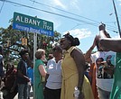 Wanda Cooper-Jones (in yellow dress) poses for photos with supporters beneath a new street sign honoring her son, Ahmaud Arbery, that was unveiled Aug. 9 in Brunswick, Ga.